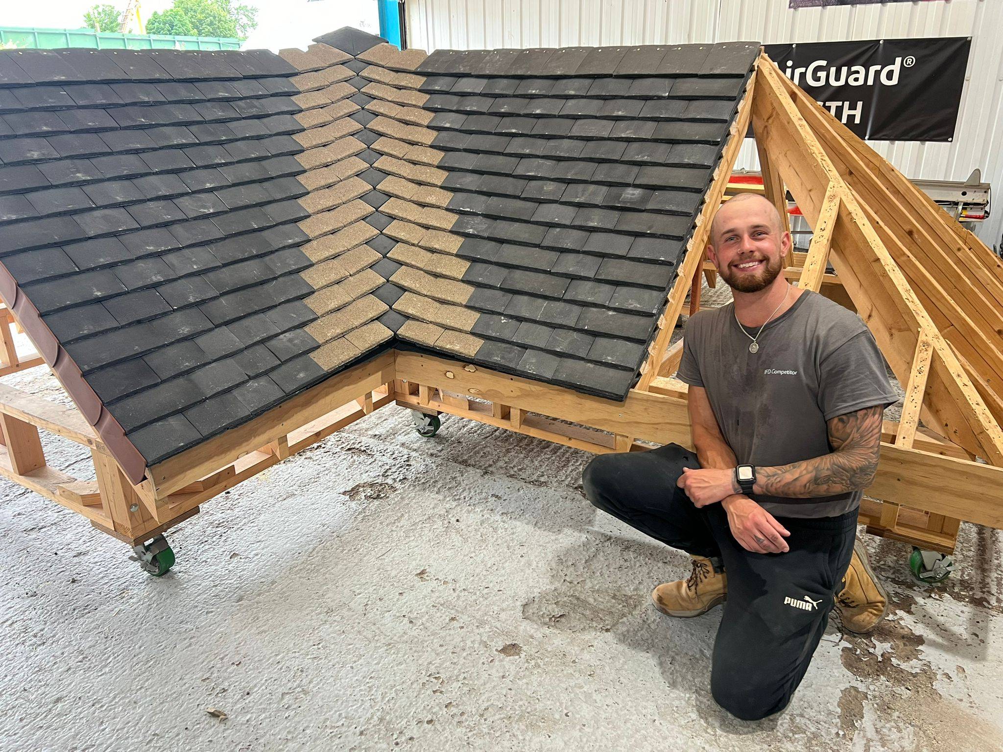 Image shows a male roofer kneeling in front of a roofing rig